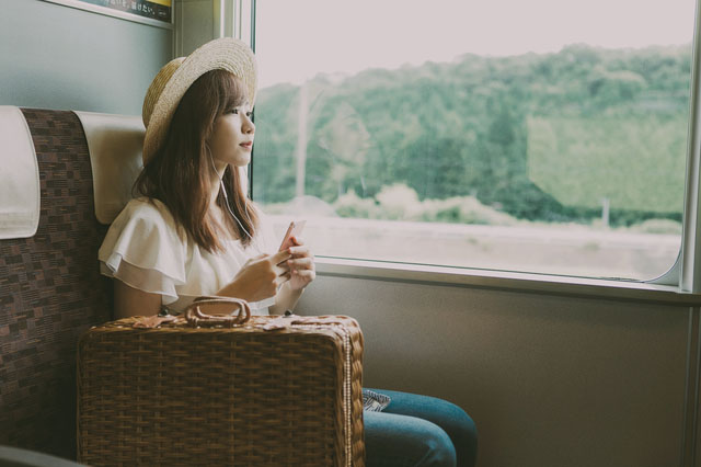 電車の窓から景色を見る女性