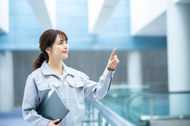 指をさす作業着の女性
