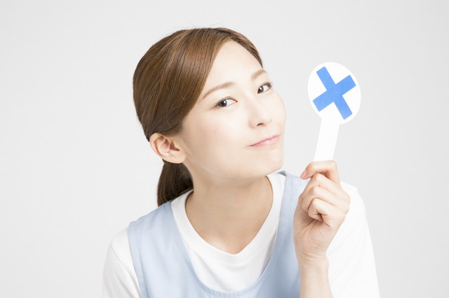バツマークを掲げる女性